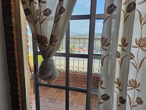 A window with a view of a brick wall and a metal railing.