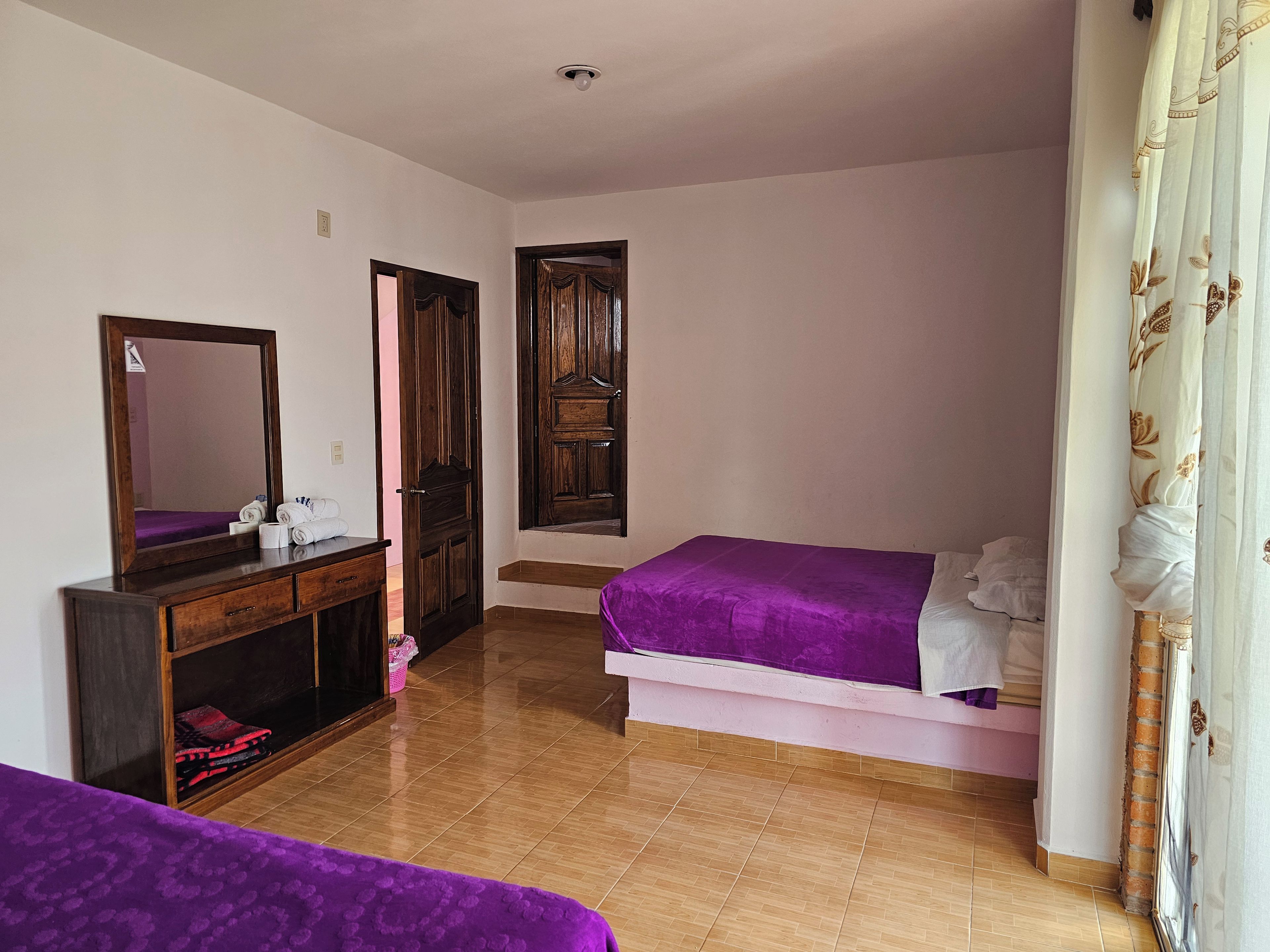 Un dormitorio con cama, cómoda, espejo y puerta.