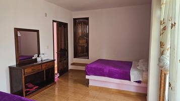Un dormitorio con cama, cómoda, espejo y puerta.