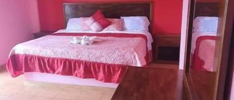 Un dormitorio con una cama, un aparador de madera y un espejo.