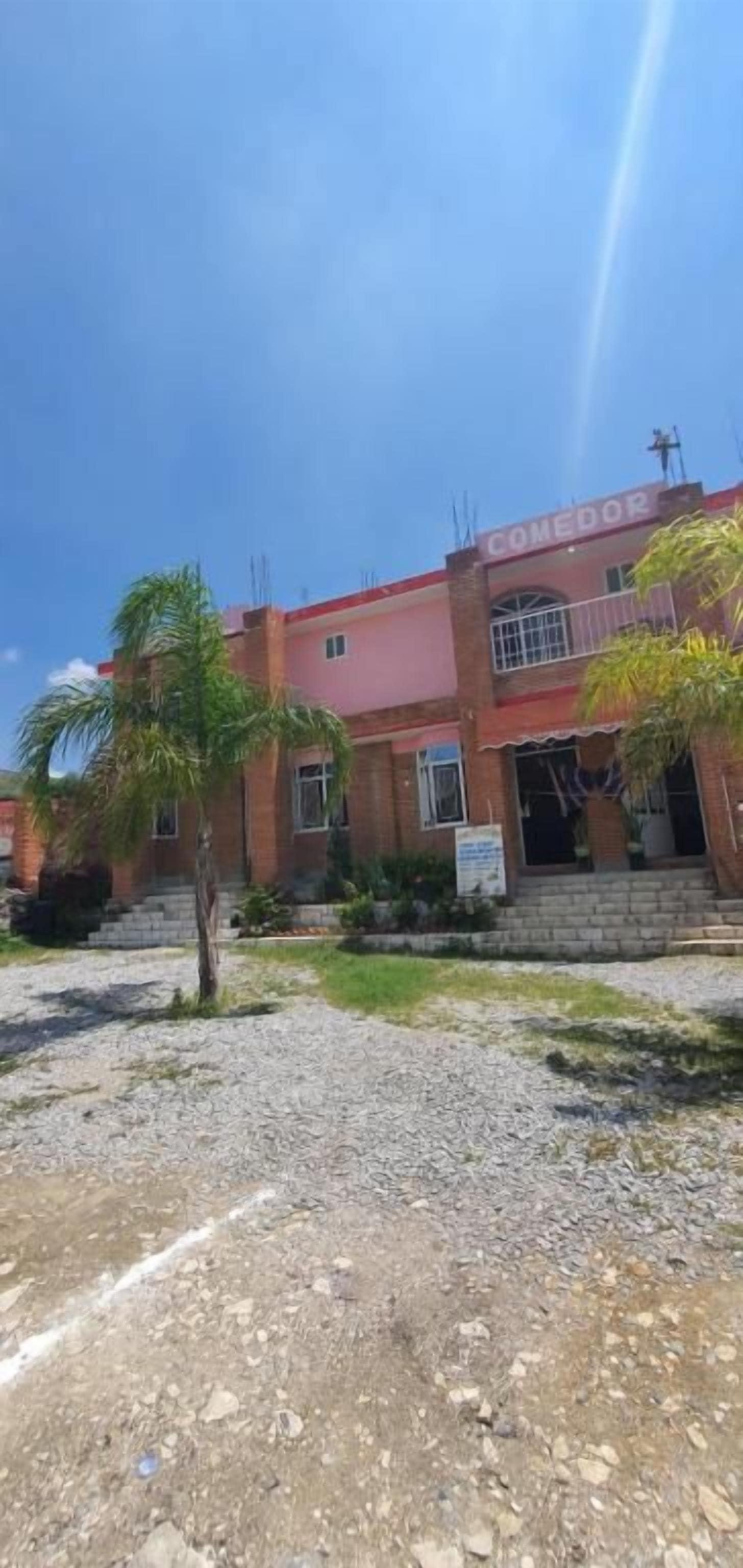 Un edificio con un letrero que dice 'COMEDOR' y un camino de entrada de grava.