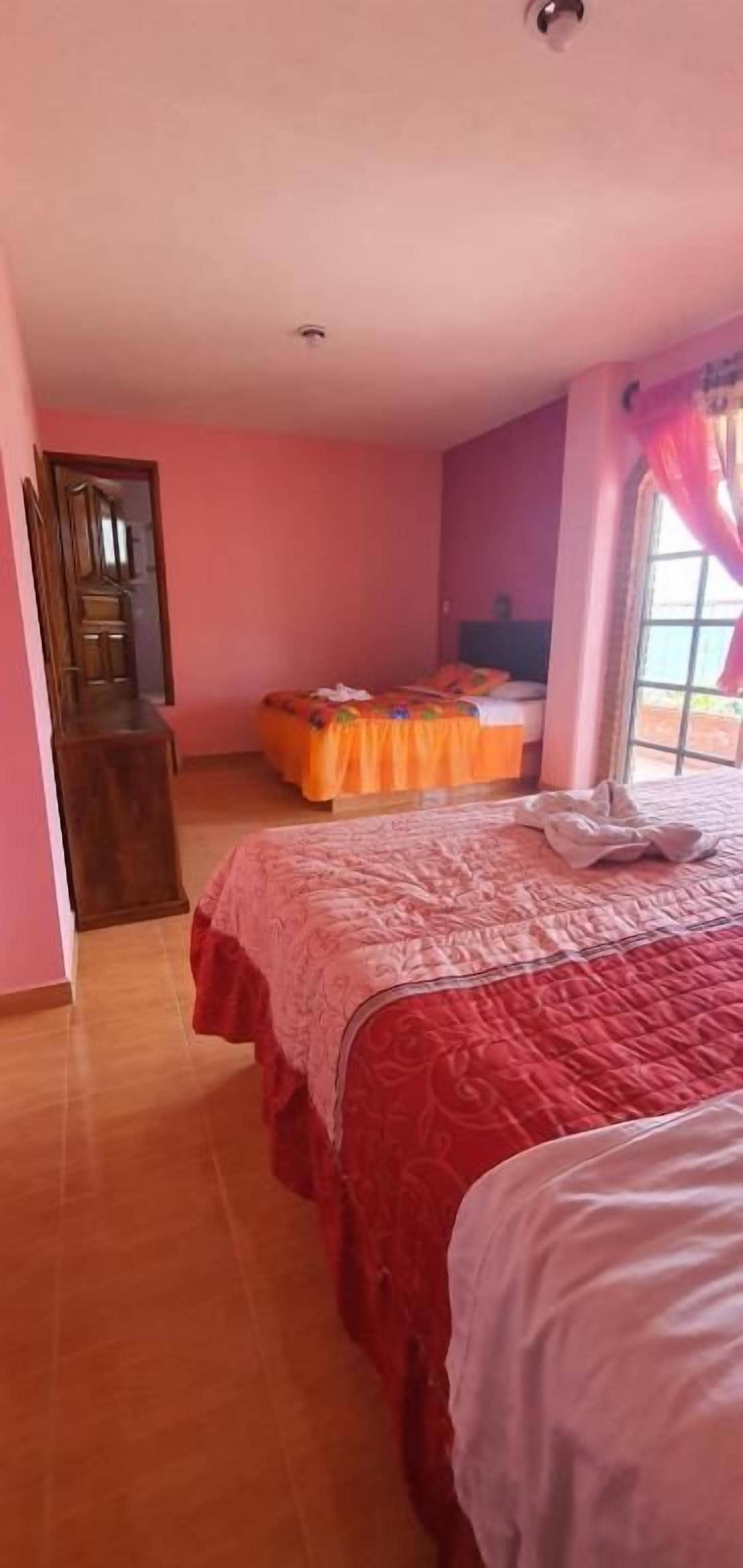 Un dormitorio con cama, cómoda y ventana con cortinas.