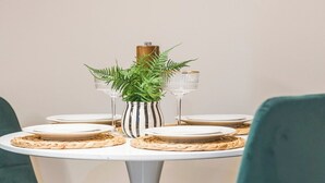 Een eettafel met borden, glazen en een gestreepte vaas met een plant.
