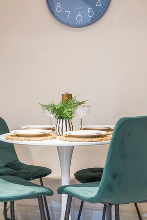 Ein Esstisch mit Tellern, Gläsern und einer gestreiften Vase mit Pflanze.
