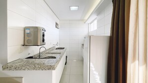 Baño de hotel estrecho con lavamanos integrado, espejo y toallero.