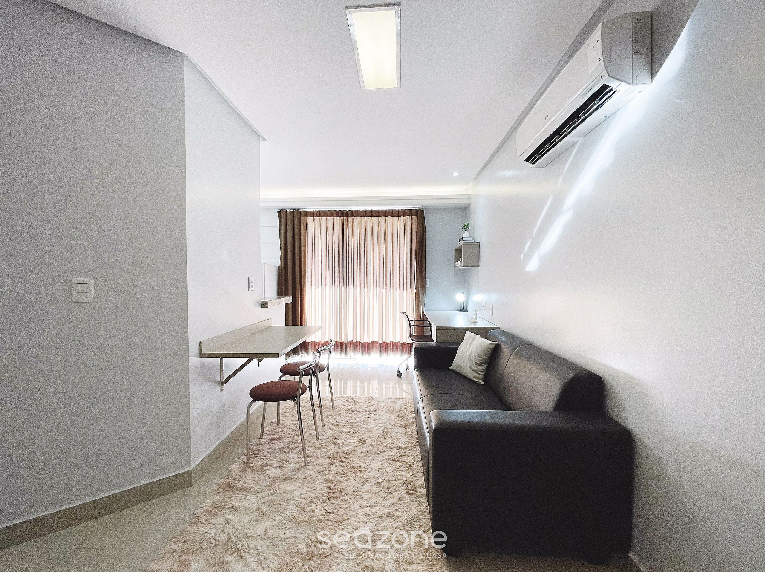 Un espace de vie moderne et compact comprenant un coin repas, un canapé et une petite kitchenette.
