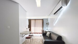 Un espacio habitable moderno y funcional con comedor, sofá y pequeña cocina.