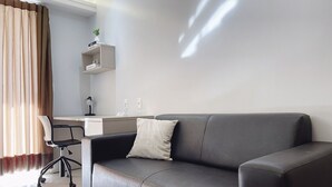 Una sala de estar moderna con un sofá gris, un escritorio y una silla.