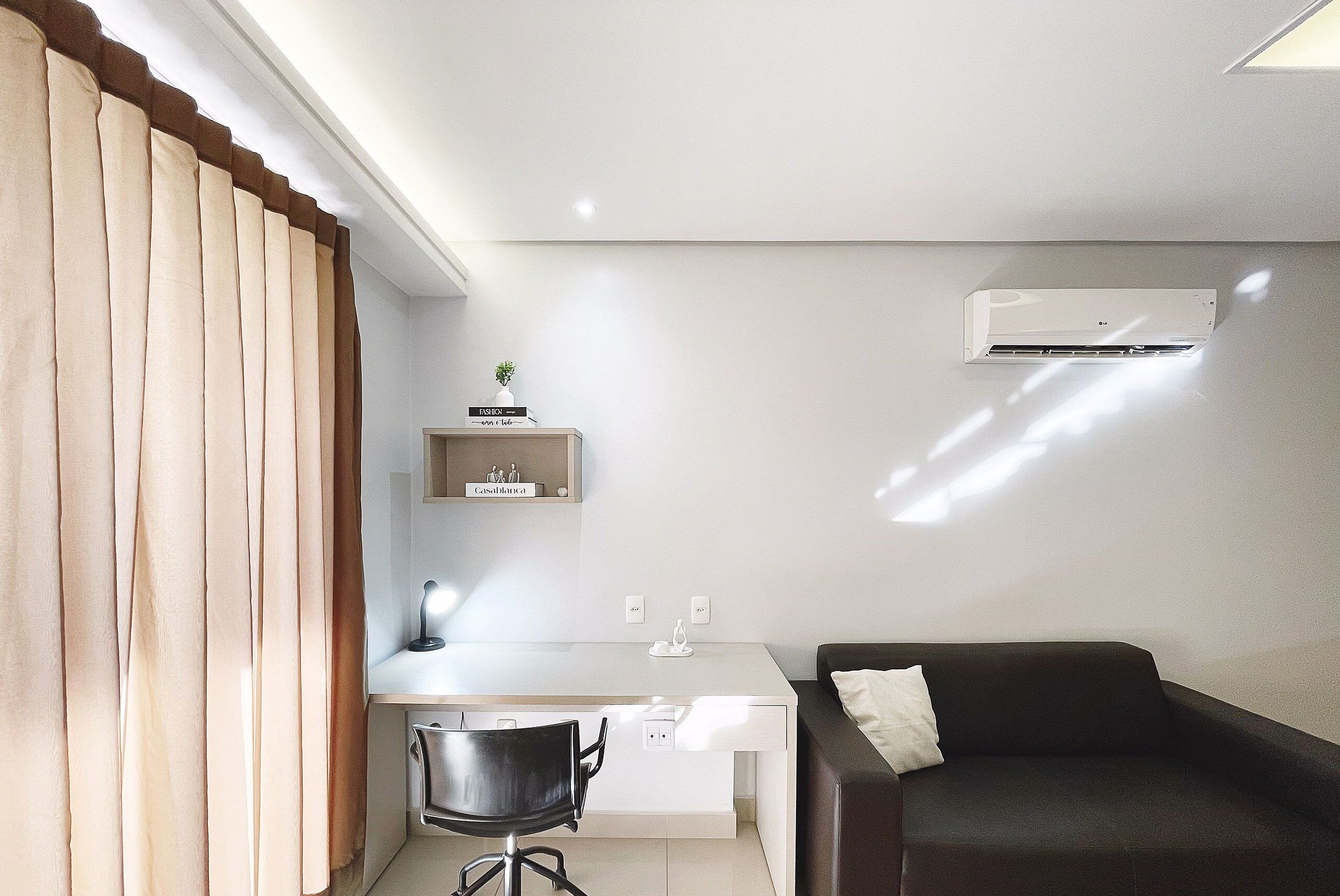 Een moderne kamer met een bureau, stoel en een donkere bank.
