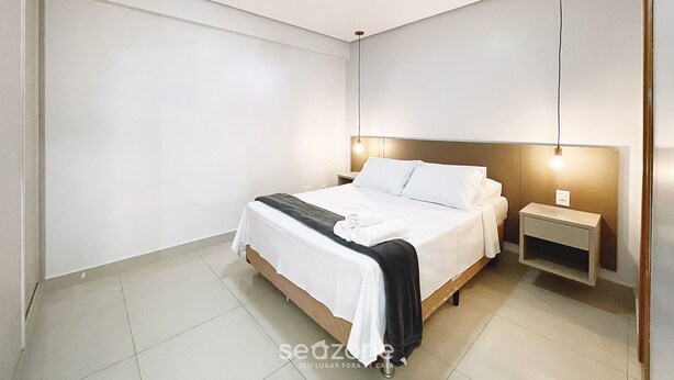 Un dormitorio moderno con una cama grande, mesitas de noche y una lámpara en el techo.