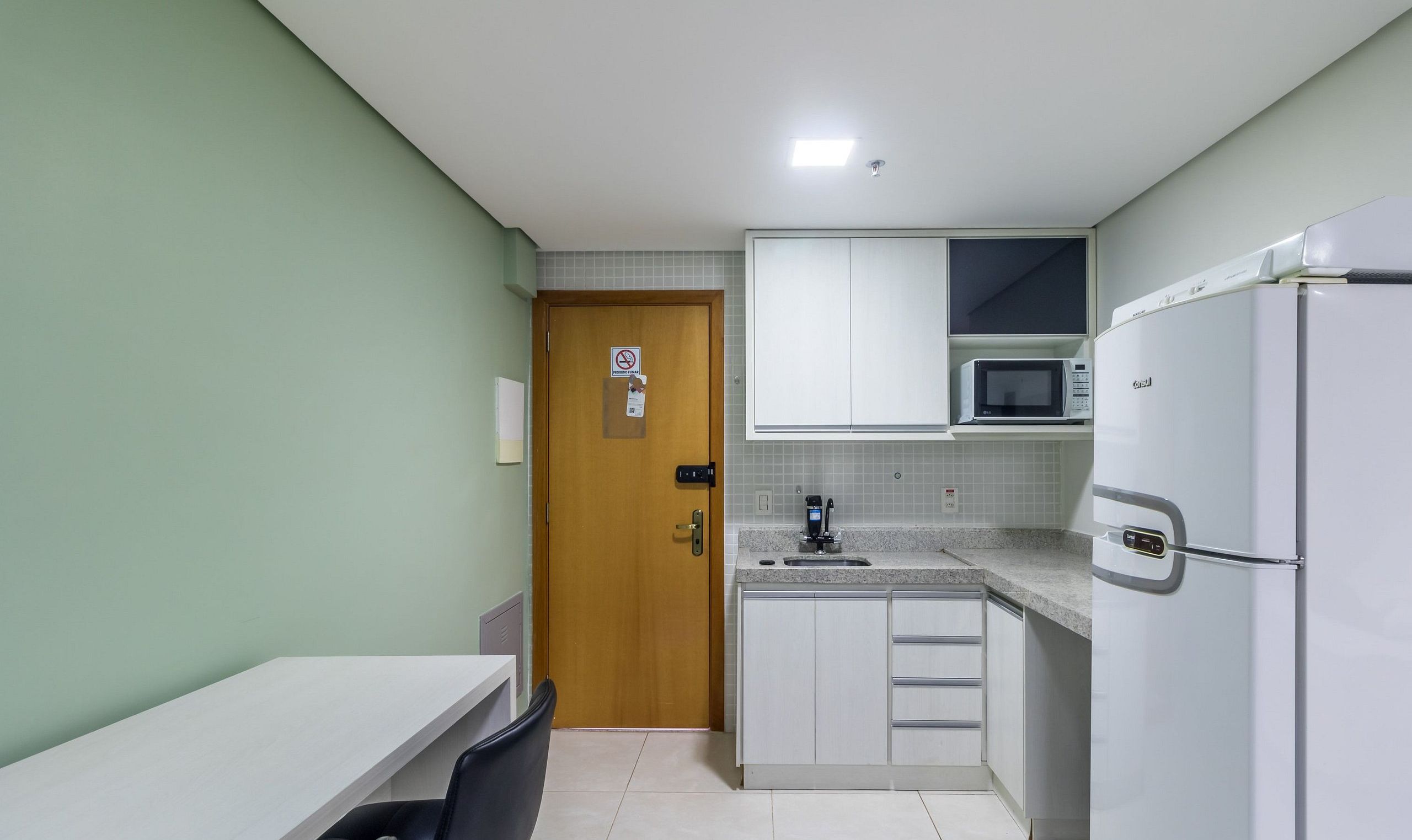 A compact kitchen with a microwave, refrigerator, and a sink.