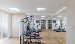 Ein Fitnessstudio mit Trainingsgeräten, Laufbändern und einer Spiegelwand.