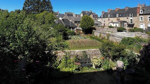A residential area with stone buildings, a garden with various plants, and a clear blue sky.