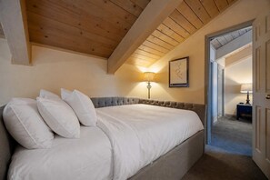 A bedroom with a large bed, a bedside lamp, and a door leading to another room. - Lofted Mountain Lookout (Steamboat Springs)