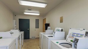 A laundry facility with multiple washing machines and dryers, fluorescent lighting, and a tiled floor. - Lofted Mountain Lookout (Steamboat Springs)