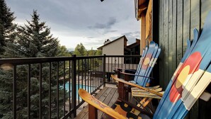 A wooden deck with a view of a mountain, a pool, and a building with a modern design. - Lofted Mountain Lookout (Steamboat Springs)