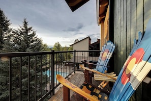 Um deck de madeira com vista para uma montanha, uma piscina e um edifício com design moderno.