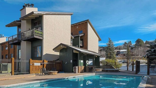 A modern two-story building with a swimming pool, outdoor seating, and a fenced area. - Lofted Mountain Lookout (Steamboat Springs)
