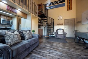 A spacious living area with a grey sofa, a dining table, and a staircase leading to an upper level. - Lofted Mountain Lookout (Steamboat Springs)