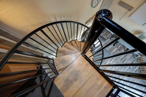 A spiral staircase with wooden steps and black metal railings. - Lofted Mountain Lookout (Steamboat Springs)
