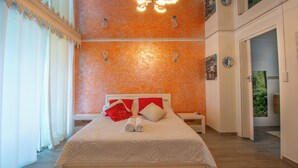 A bedroom with a bed, a nightstand, and a door leading to another room. - Rêve Bleu 10 - Clim - Proche plage (LE DIAMANT)