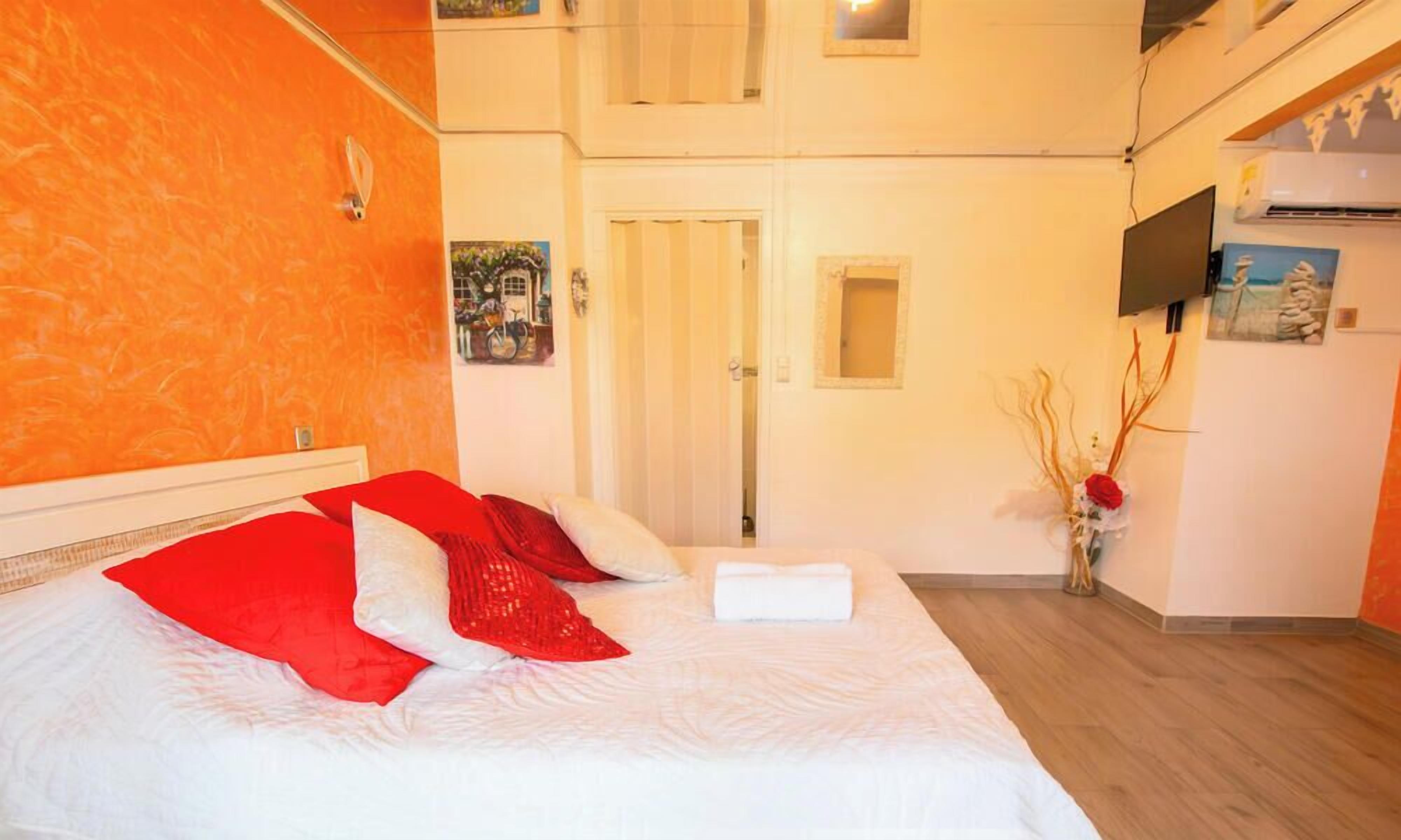 Hotellihuone, jossa on sänky, ovi, litteänäyttöinen televisio ja pieni ikkuna.