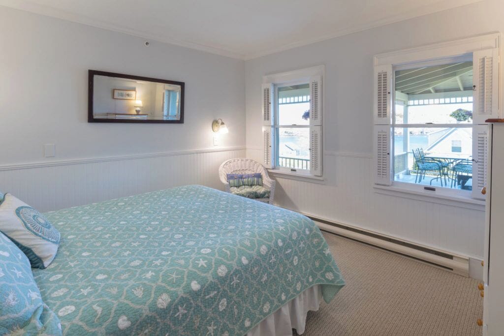 A bedroom with a bed, a chair, a window, and a door.