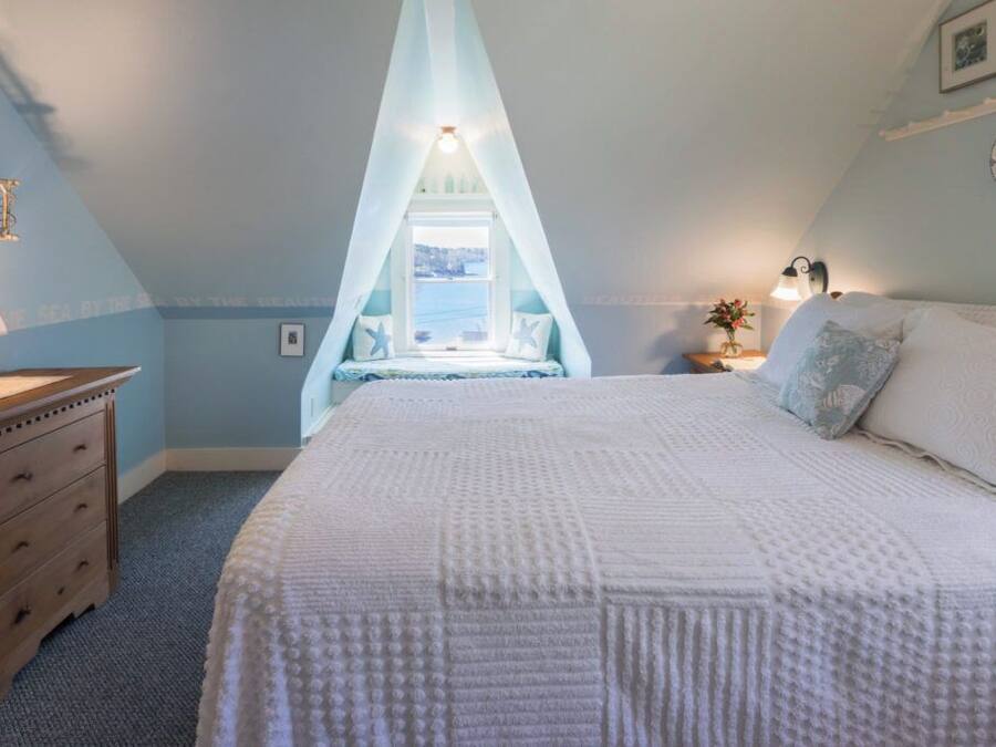 Quarto com uma cama grande, mesa de cabeceira, cômoda e janela com vista.