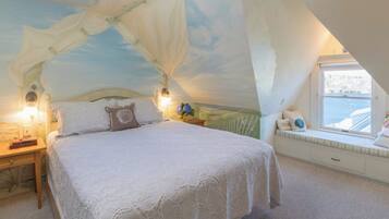 Un dormitorio con cama con dosel, lámparas de noche, un asiento junto a la ventana y vistas al exterior.