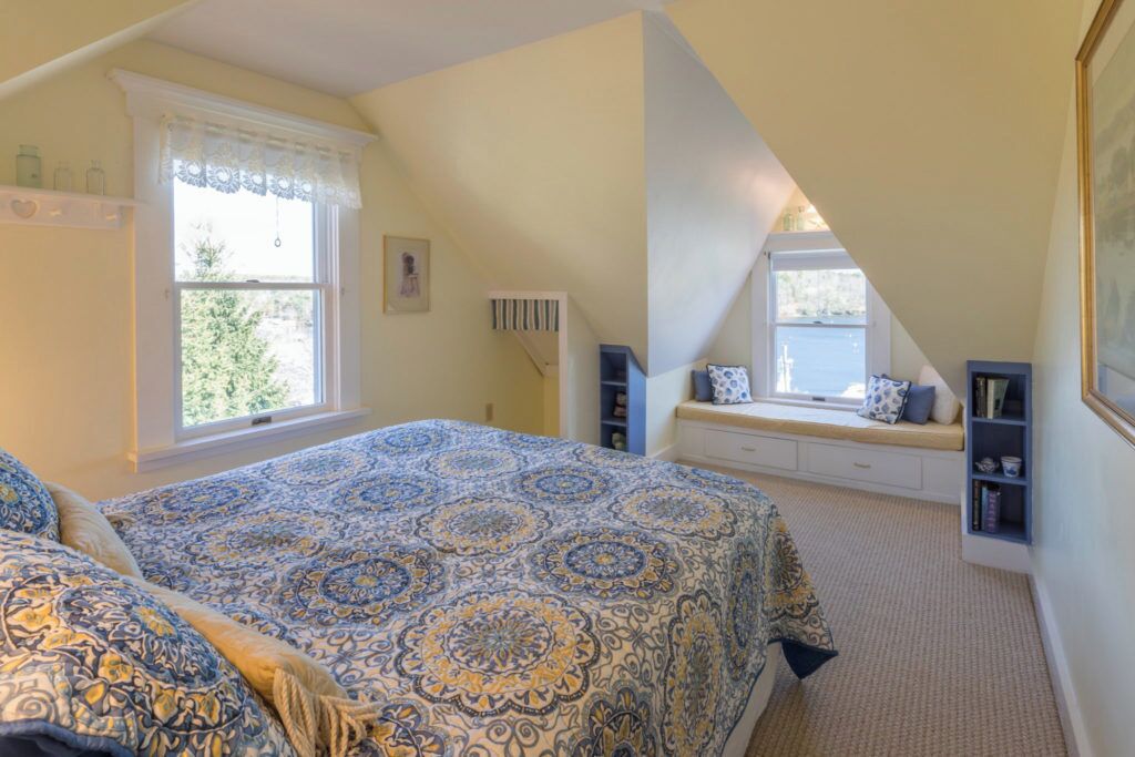 Une chambre à coucher avec un grand lit, un coin lecture près de la fenêtre et une bibliothèque.