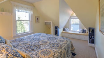 Une chambre à coucher avec un grand lit, un coin lecture près de la fenêtre et une bibliothèque.