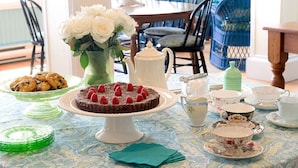 A dining table with a cake, cookies, and a vase of flowers. - Five Gables Inn (East Boothbay)
