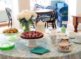 Una mesa de comedor con un pastel, galletas y un florero.