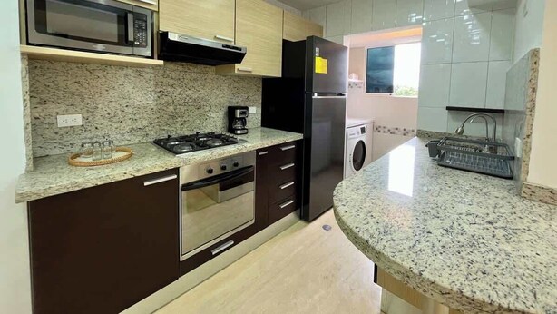A modern kitchen with granite countertops, stainless steel appliances, and a built-in washer and dryer. - Vistas Increibles y Confort en El Rosal (Caracas)