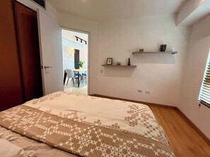 Ein Schlafzimmer mit Bett, einer Tür, einem Fenster und Blick auf einen Außenbereich.