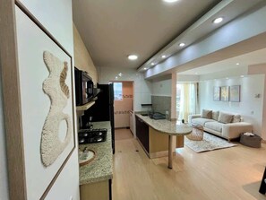 A modern kitchen with a central island, a dining area with a sofa, and a living room with a couch.