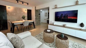 A modern living room with a sofa, a dining area, and a TV mounted on the wall. - Vistas Increibles y Confort en El Rosal (Caracas)