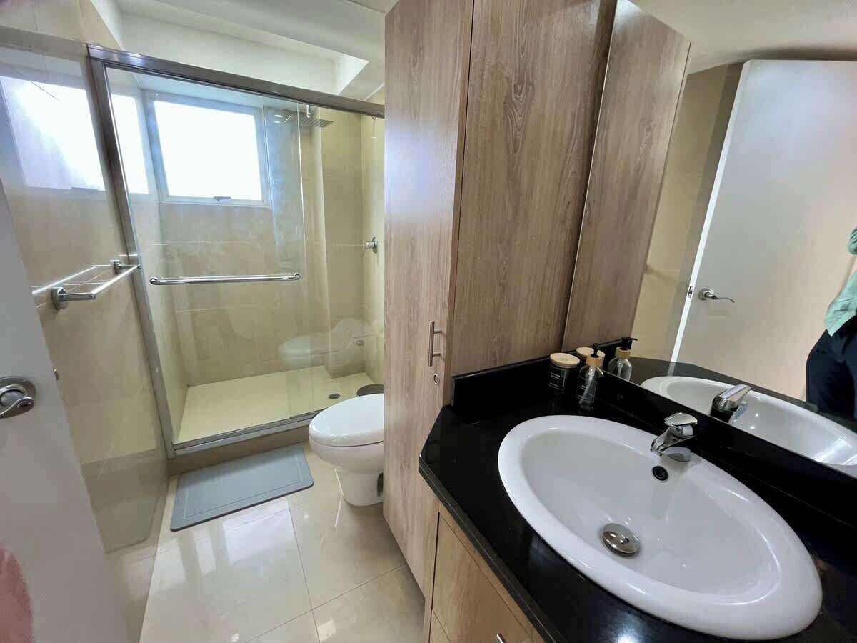 Un baño con ducha, inodoro y dos lavamanos.