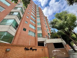 A high-rise building with a brick facade and multiple windows. - Vistas Increibles y Confort en El Rosal (Caracas)