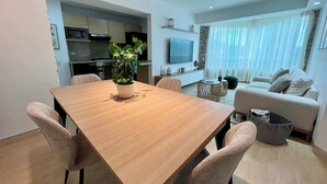 A modern living space with a dining area, kitchen, and a seating area with a sofa and a TV. - Vistas Increibles y Confort en El Rosal (Caracas)