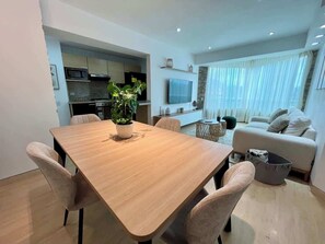A modern living space with a dining area, kitchen, and a seating area with a sofa and a TV. - Vistas Increibles y Confort en El Rosal (Caracas)
