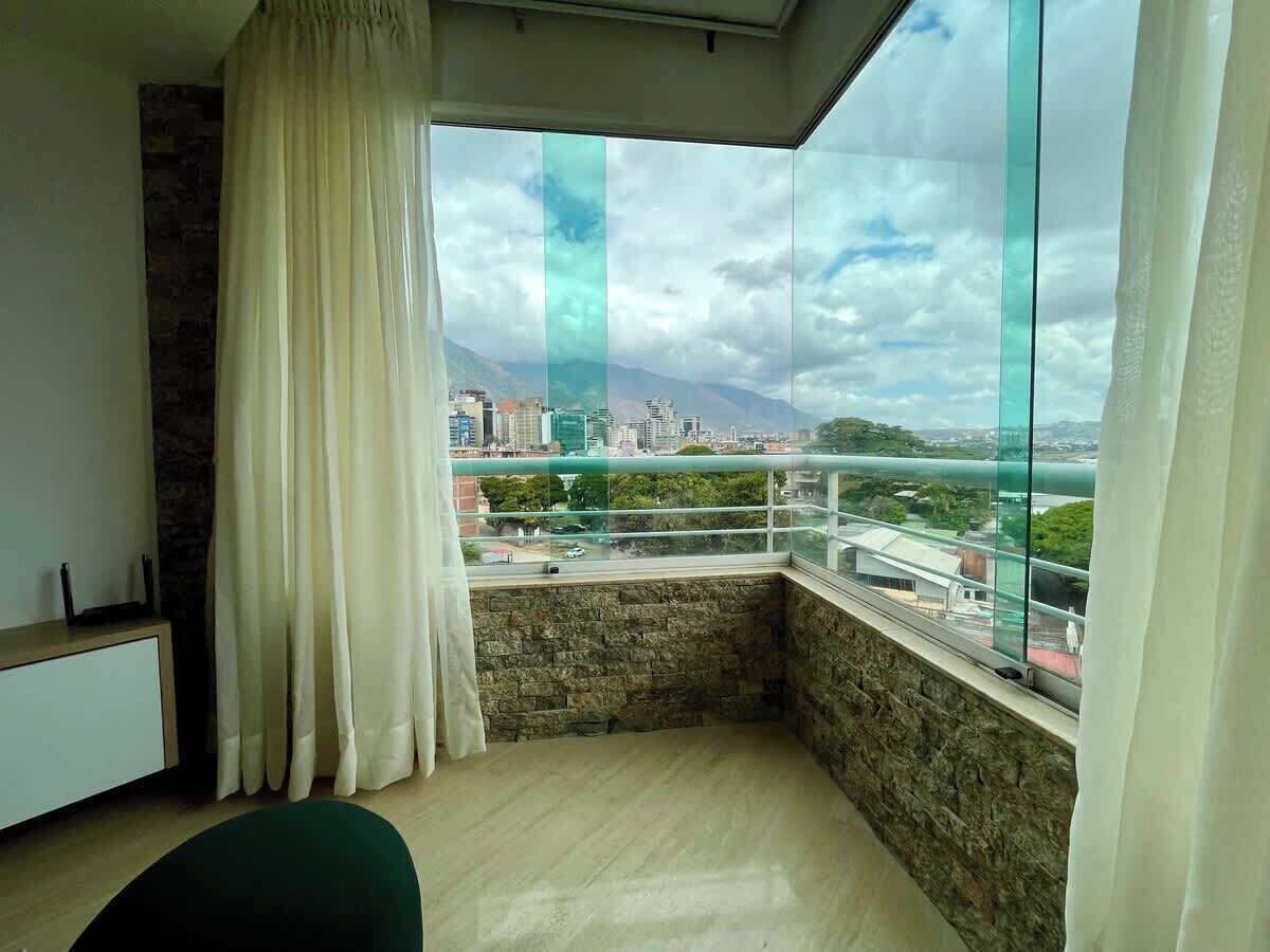 Une pièce avec vue sur le paysage urbain, grâce à de grandes fenêtres, un mur en pierre et un bureau moderne.