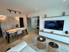 Una sala moderna con comedor, televisor de pantalla plana en la pared y una pared de acento de piedra.