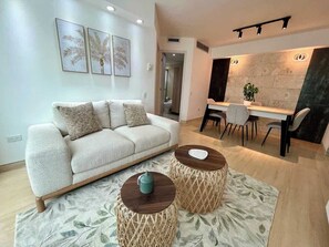 Ein modernes Wohnzimmer mit einer Couch, zwei runden Holztischen und einem Essbereich mit Tisch und Stühlen.