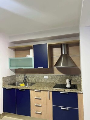 Eine Küche mit Granit Arbeitsplatte, Edelstahlspüle und einer Kaffeemaschine.