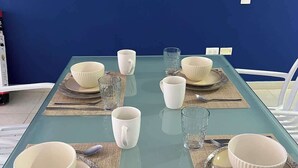 Una mesa de comedor dispuesta con cuencos blancos, vasos y cubiertos sobre individuales.