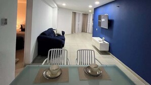 Una habitación de hotel moderna con zona de comedor, cama y baño.