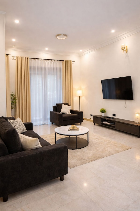 A modern living room with a sofa, a coffee table, a TV, and a lamp.
