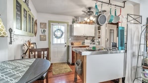 Una cucina con zona pranzo, pavimento in legno e una porta bianca.
