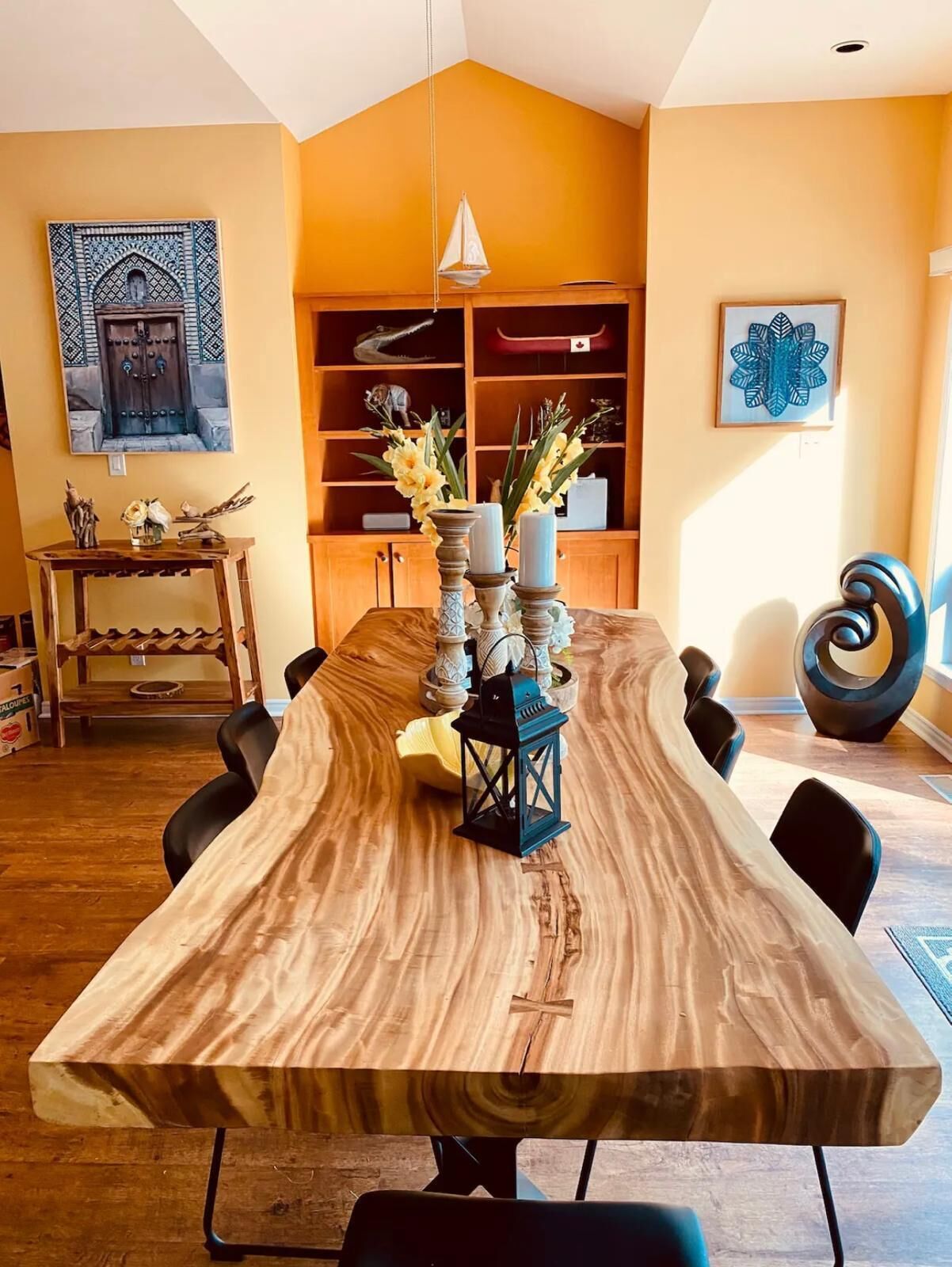 A dining area with a long wooden table, black chairs, and a central candle holder with candles.